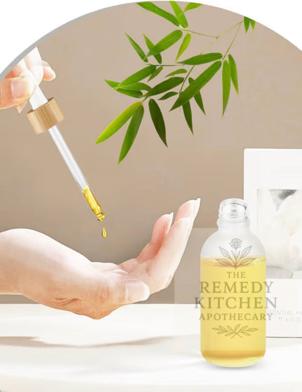 dropper with tincture or oil liquid over skin, bottle labeled 'The Remedy Kitchen Apothecary' in the background